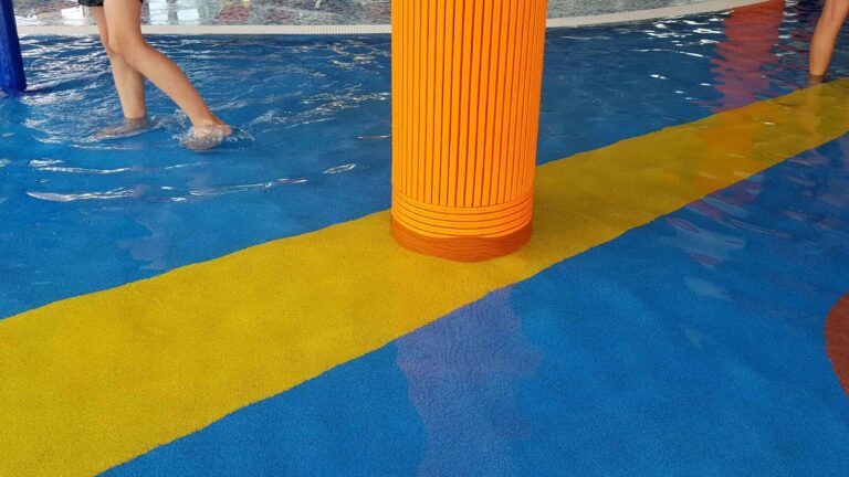 Orange TECNA-Säulenverkleidungen in einer Schwimmhalle
